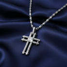 Silver cross pendant necklace with an Austrian crystal in the middle on a blue satin background